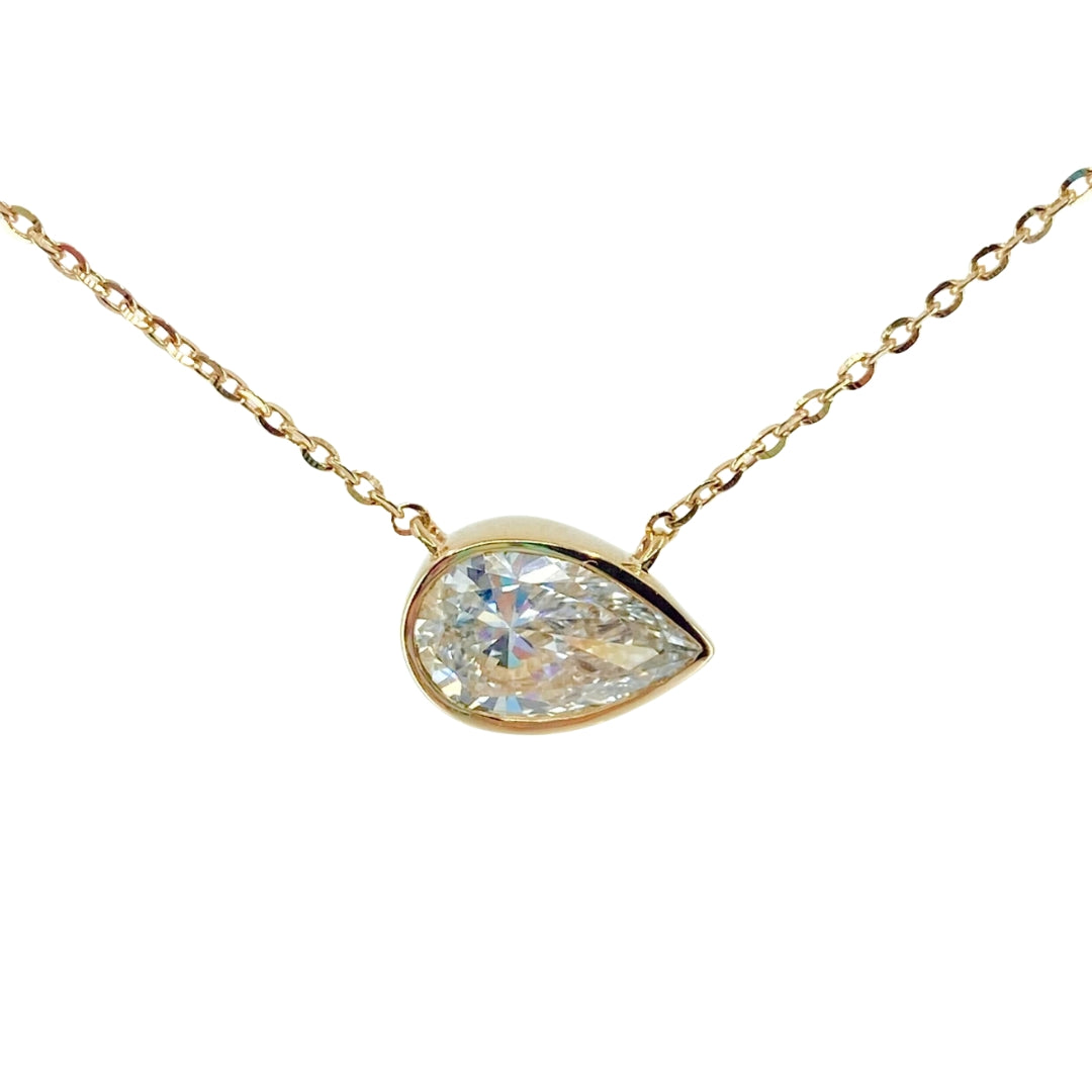 Yellow gold necklace with a bezel set pear shaped lab grown diamond shimmering from the center.