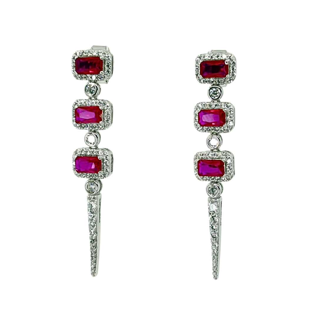 White silver drop earrings with three descending emerald cut red cz stones haloed by white czs and accented with a triangle cz drop.