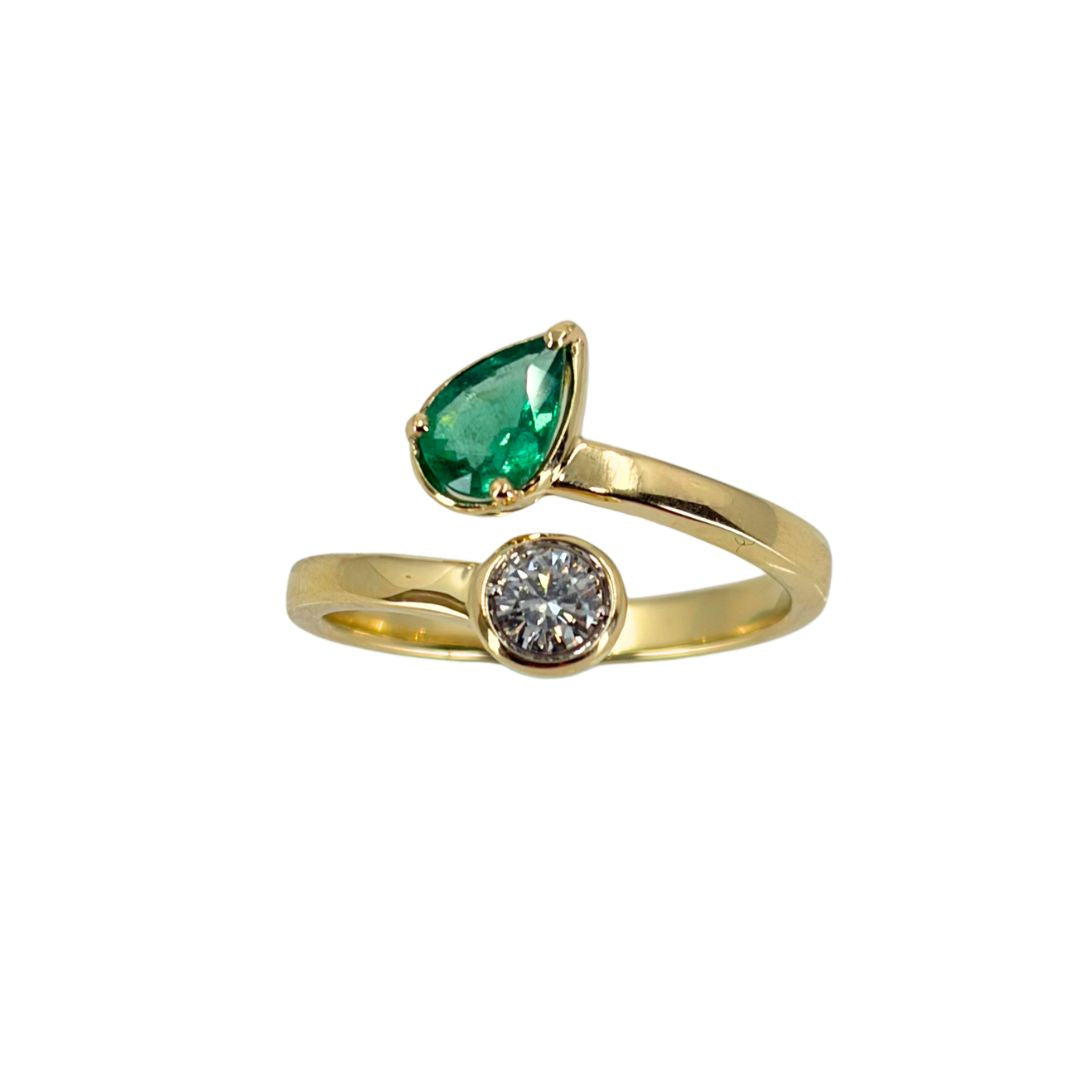 Yellow gold bypass ring set with a vibrant pear emerald at the top end and a round diamond at the lower end.