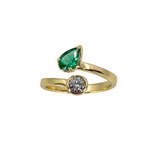 Yellow gold bypass ring set with a vibrant pear emerald at the top end and a round diamond at the lower end.