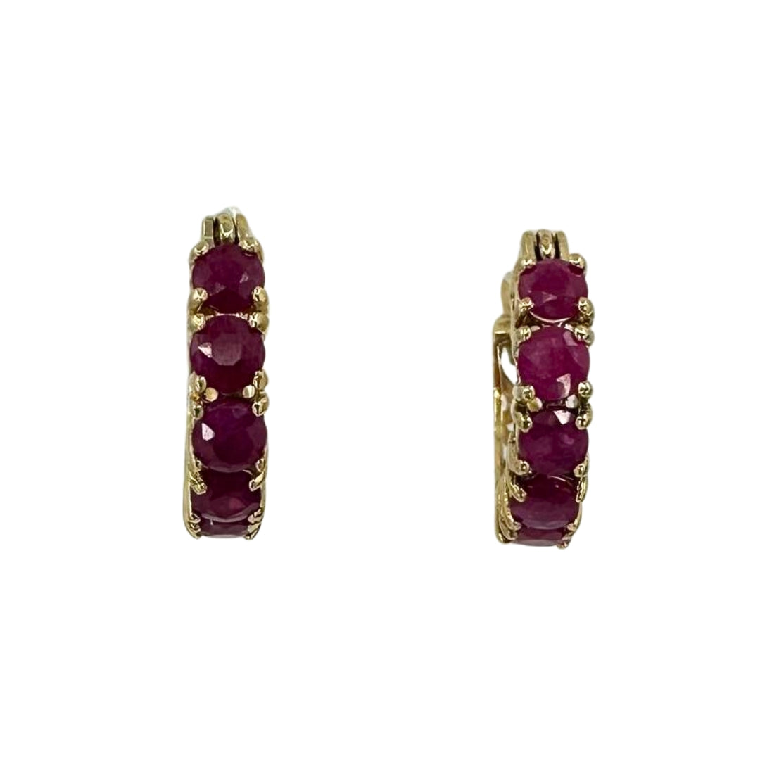Front view of yellow gold hoop earrings set with vibrant red rubies.