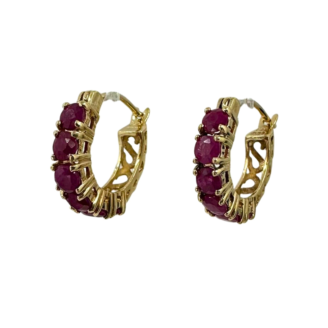 Side view of yellow gold hoop earrings set with six round rubies each.