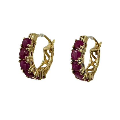 Side view of yellow gold hoop earrings set with six round rubies each.