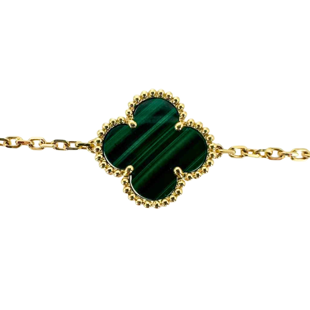 Vibrant green malachite stone in a quatrefoil clover shape surrounded by its yellow gold setting.
