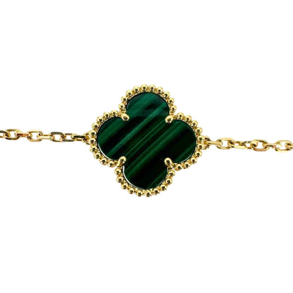 Vibrant green malachite stone in a quatrefoil clover shape surrounded by its yellow gold setting.