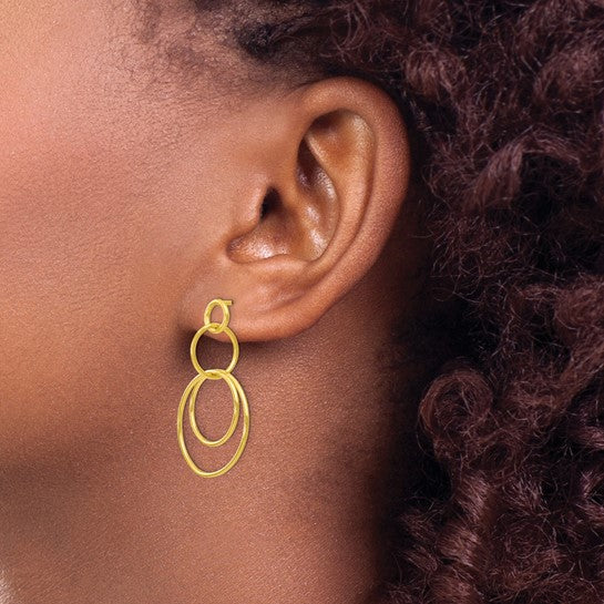 Dangle gold toned sterling silver earrings with a double loop design on model.