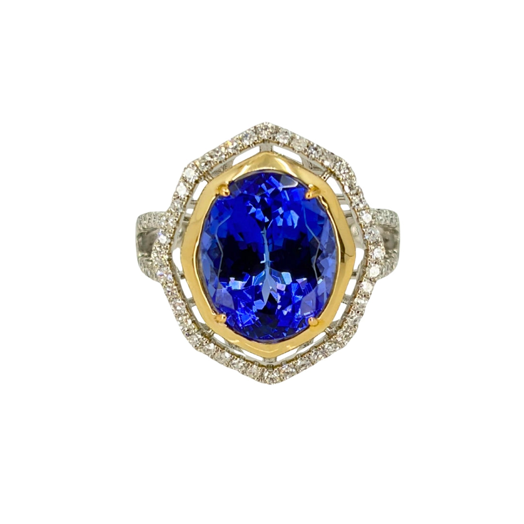 White gold ring set with diamonds along the shank and in a halo along with yellow gold around the deep blue tanzanite stone centerpiece.