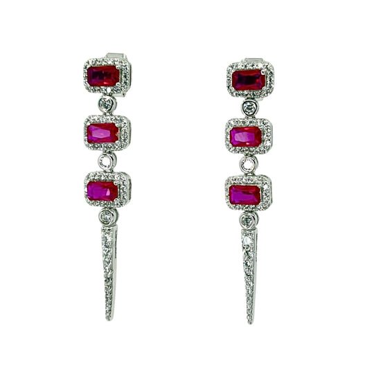 White silver drop earrings with three descending emerald cut red cz stones haloed by white czs and accented with a triangle cz drop.