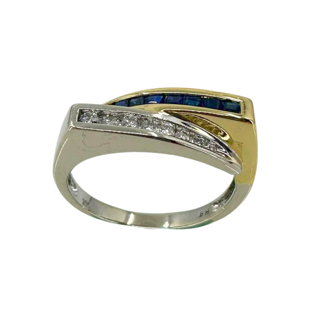 Two tone gold bypass ring with a white gold channel setting of round diamonds and shank bypassed by blue sapphires set in yellow gold.