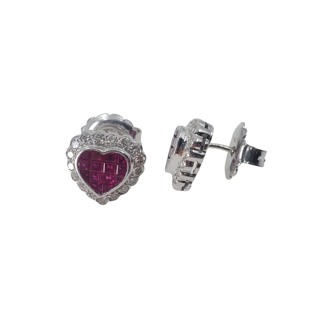 Side view of white gold heart shaped stud earrings set with a ruby center and an outer circling of diamonds.