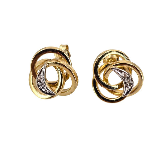Two tone gold earrings in a love knot design set with shimmering diamonds.